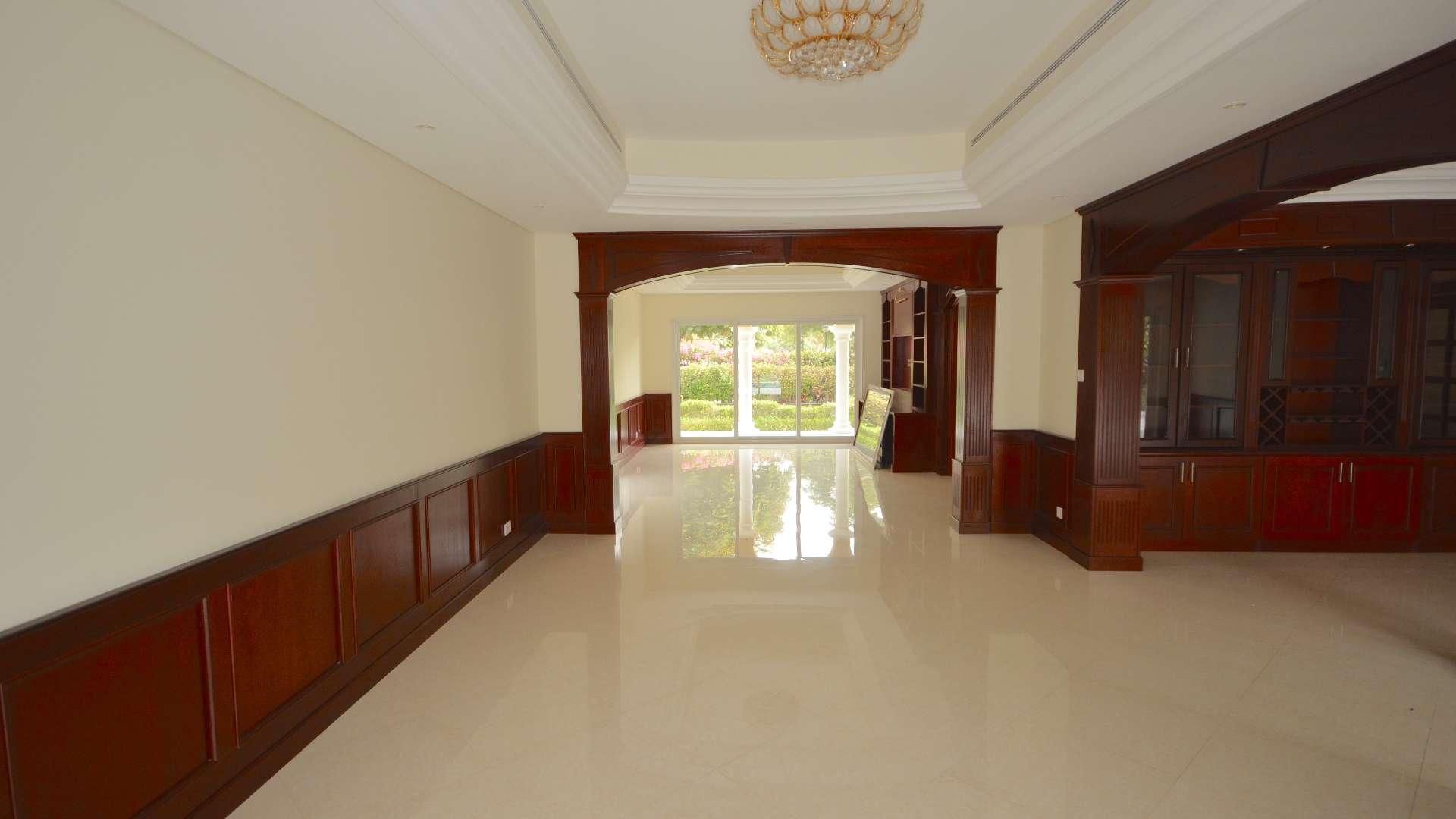 "Front view of spacious villa in Green Community West with lush garden and gated entrance.",Spacious villa interior with elegant wood paneling and garden view in Green Community West