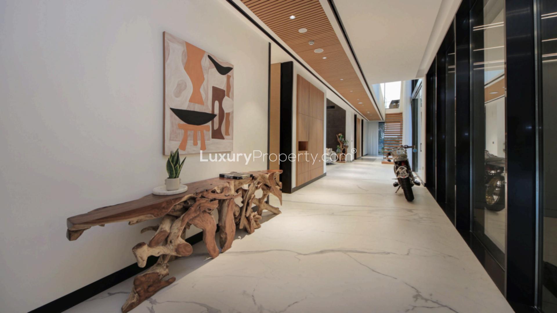 "Luxury villa hallway with sleek motorcycle display in Jumeirah Golf Estates, Sienna Lakes.",Modern hallway with artistic decor in 5-bed villa, Sienna Lakes, Jumeirah Golf Estates