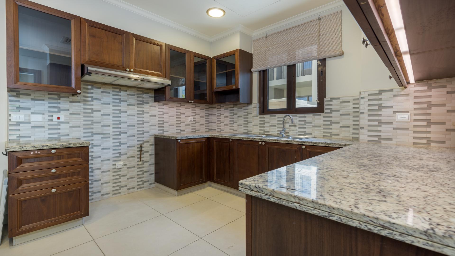 Kitchen of 5-bed villa in Arabian Ranches 2, featuring wooden cabinets and granite countertops