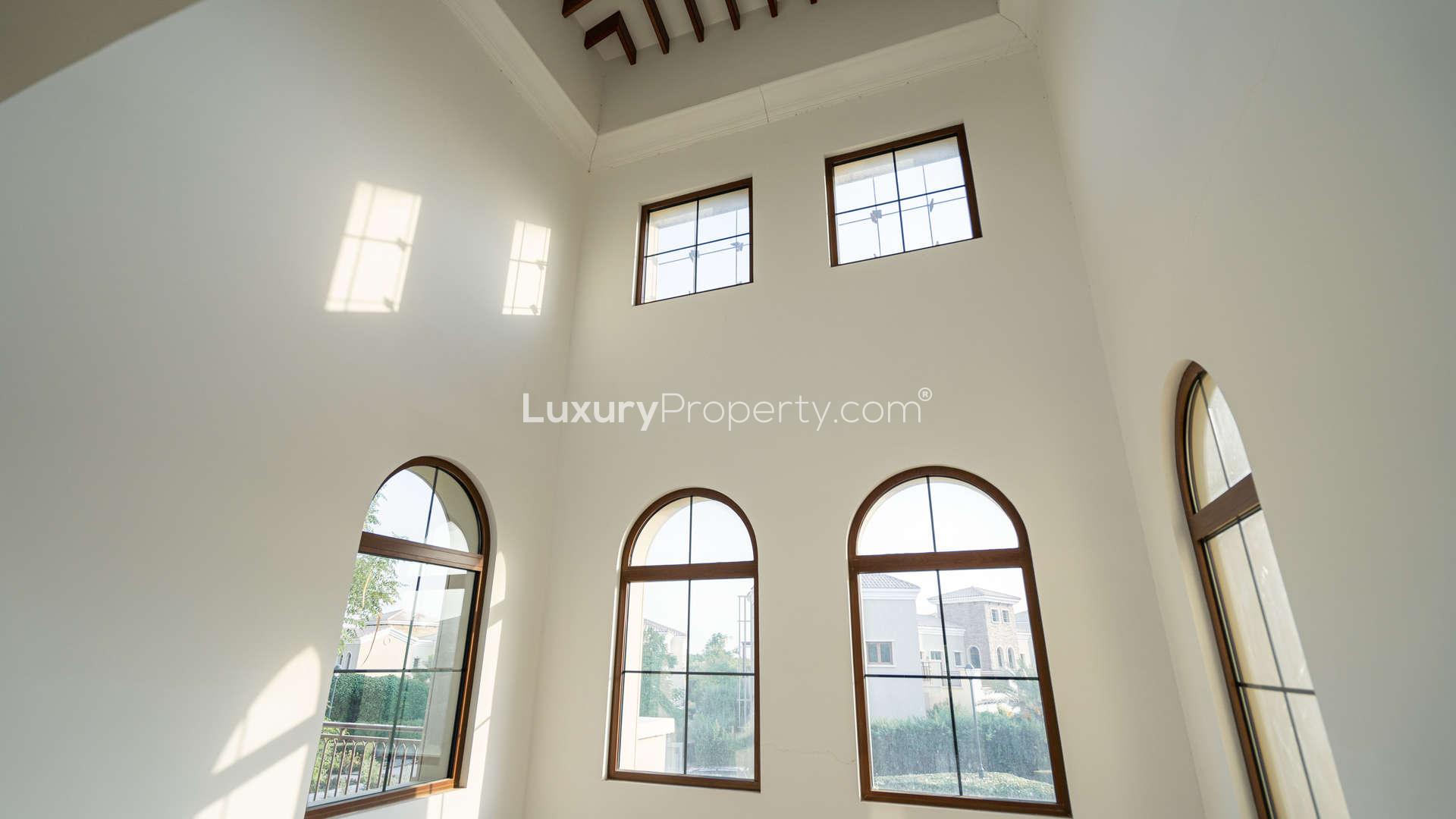 "Elegant stone facade of Lime Tree Valley villa in Jumeirah Golf Estates, Dubai real estate.",Interior view of high-ceiling windows in Lime Tree Valley villa, Jumeirah Golf Estates