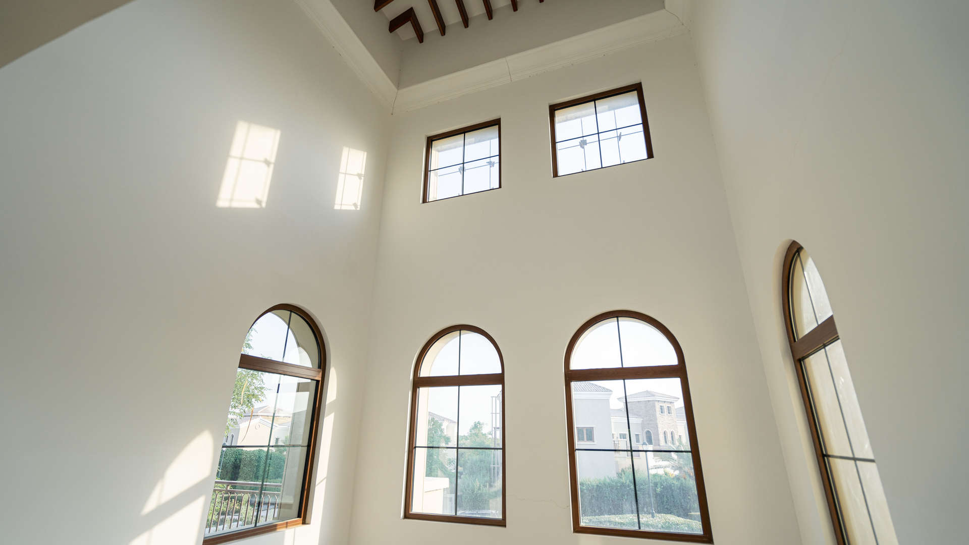 "Elegant stone facade of Lime Tree Valley villa in Jumeirah Golf Estates, Dubai real estate.",Interior view of high-ceiling windows in Lime Tree Valley villa, Jumeirah Golf Estates
