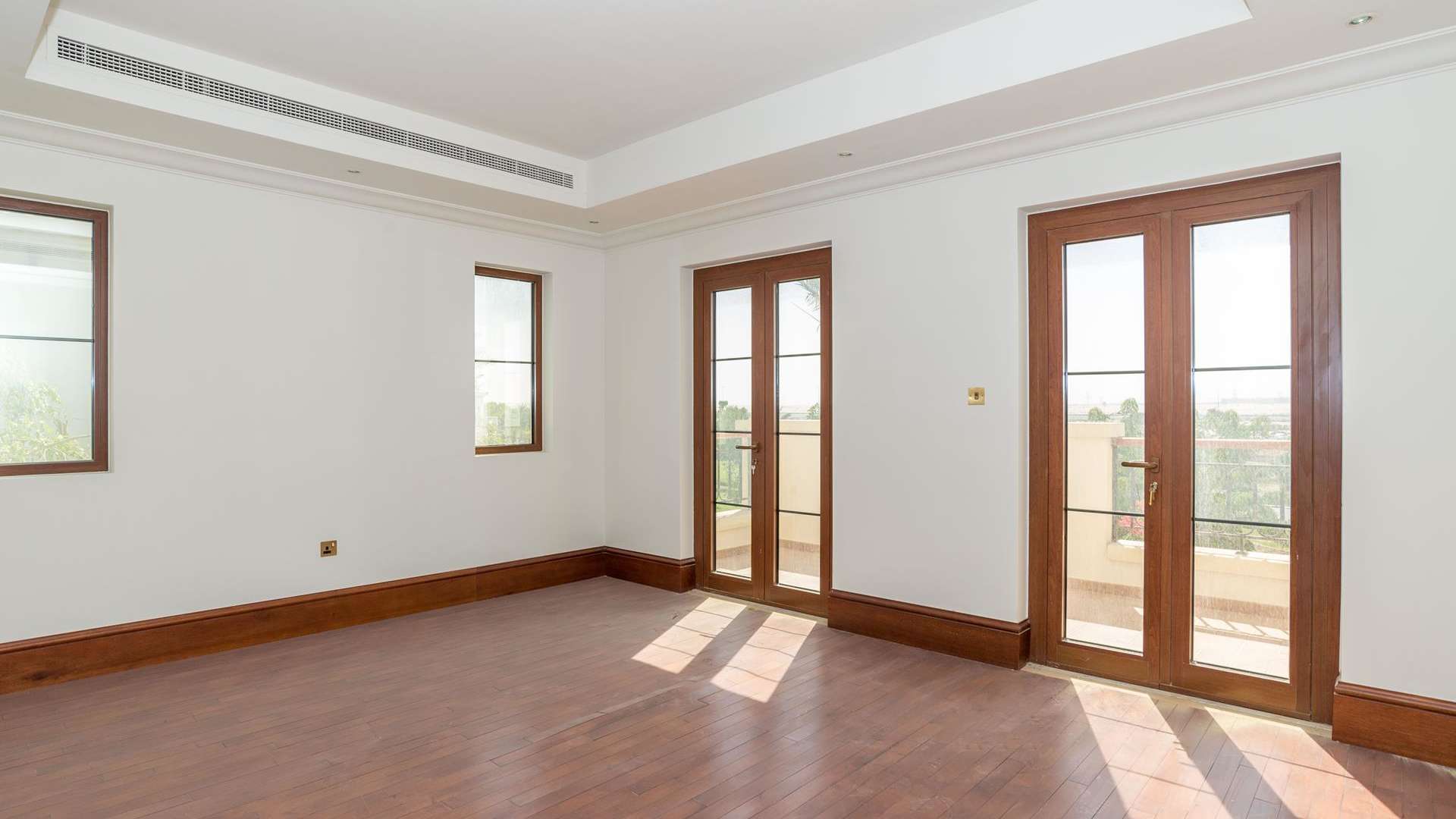 Empty room with wooden floors and French doors in Lime Tree Valley villa, Jumeirah Golf Estates