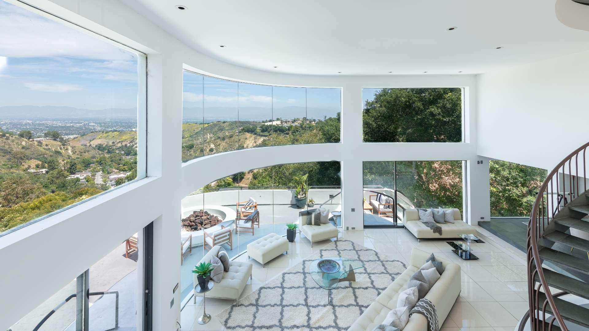 Spacious living area with panoramic views, modern furniture, and spiral staircase in Bel Air Villa