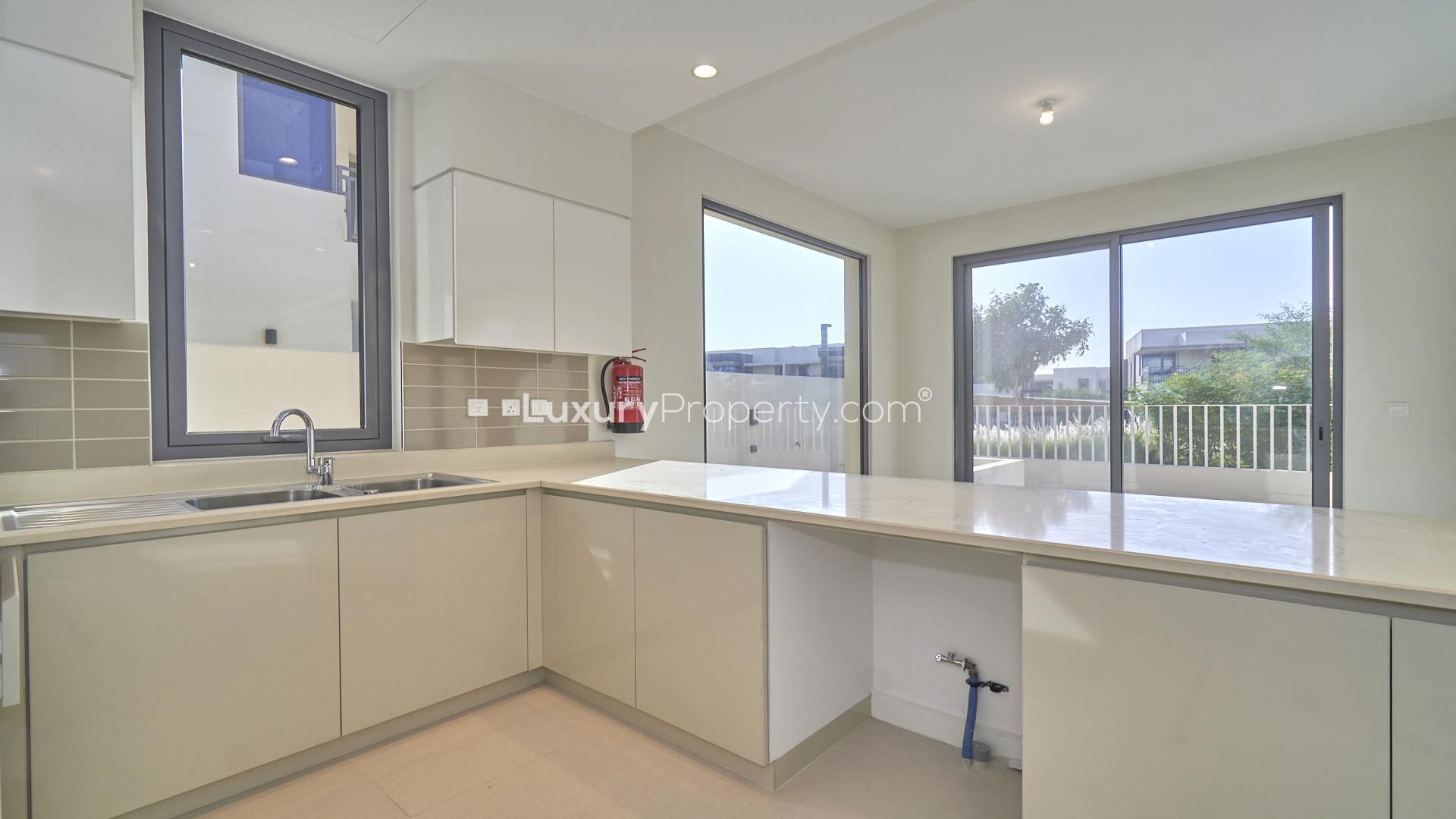 Modern kitchen in 5-bedroom villa, Maple at Dubai Hills Estate, featuring large windows and countertops