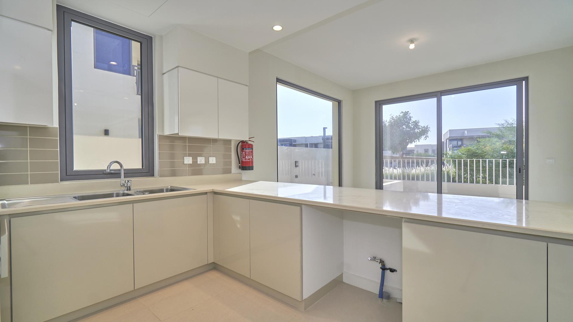 Modern kitchen in 5-bedroom villa, Maple at Dubai Hills Estate, featuring large windows and countertops