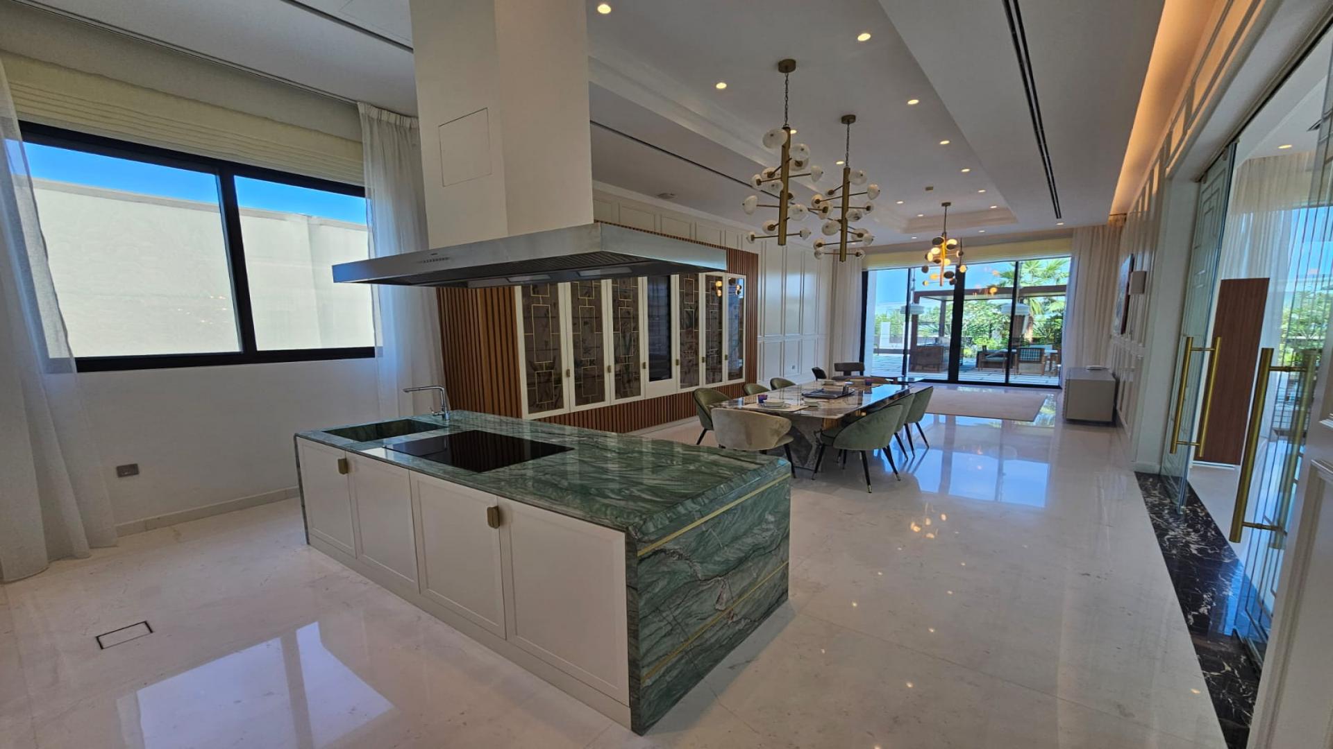 "Spacious dining area in furnished mansion, Dubai Hills Estate, with garden view and elegant decor.",Luxurious kitchen and dining area in bespoke Dubai Hills Estate mansion with park view