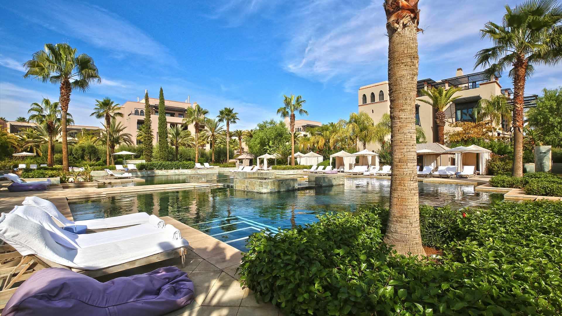 Luxurious poolside view at Villa Wazn, Four Seasons Marrakech, surrounded by palm trees