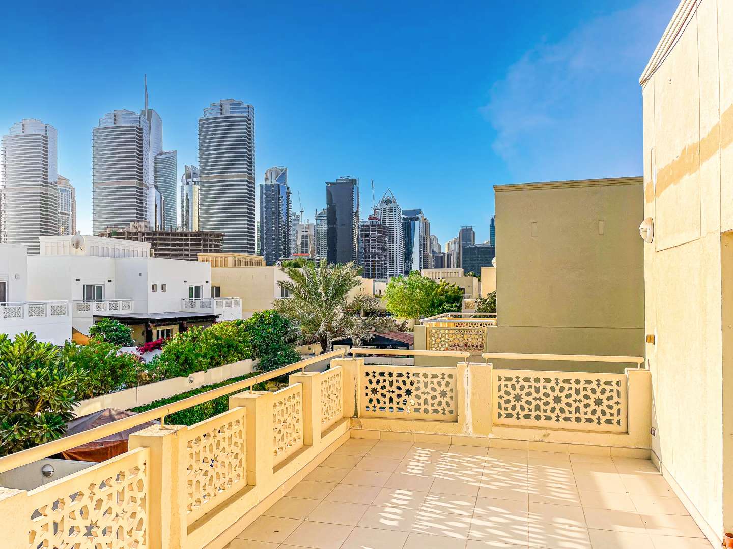 Villa exterior with driveway in Meadows 5, featuring palm tree and blue sky
