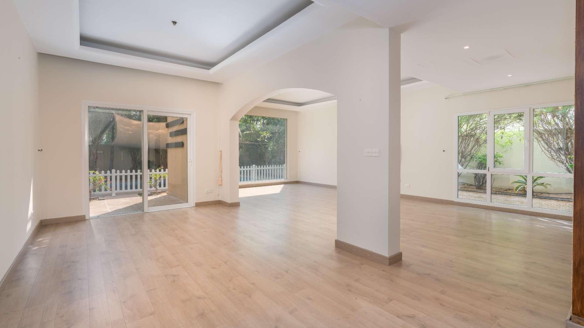 "Spacious living room with garden view in modern 5-bedroom Meadows villa, Emirates Living.",Spacious living area with wooden flooring in modern 5-bedroom villa, Meadows, Emirates Living