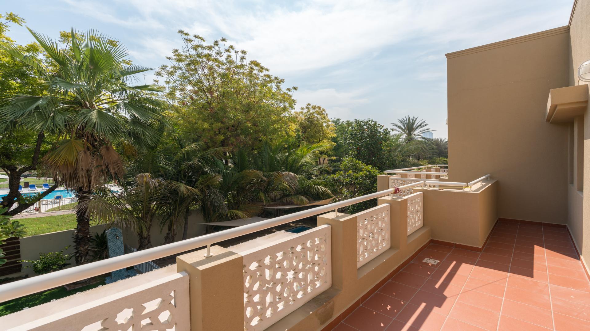 Spacious balcony view of lush garden and pool in Meadows villa, Emirates Living