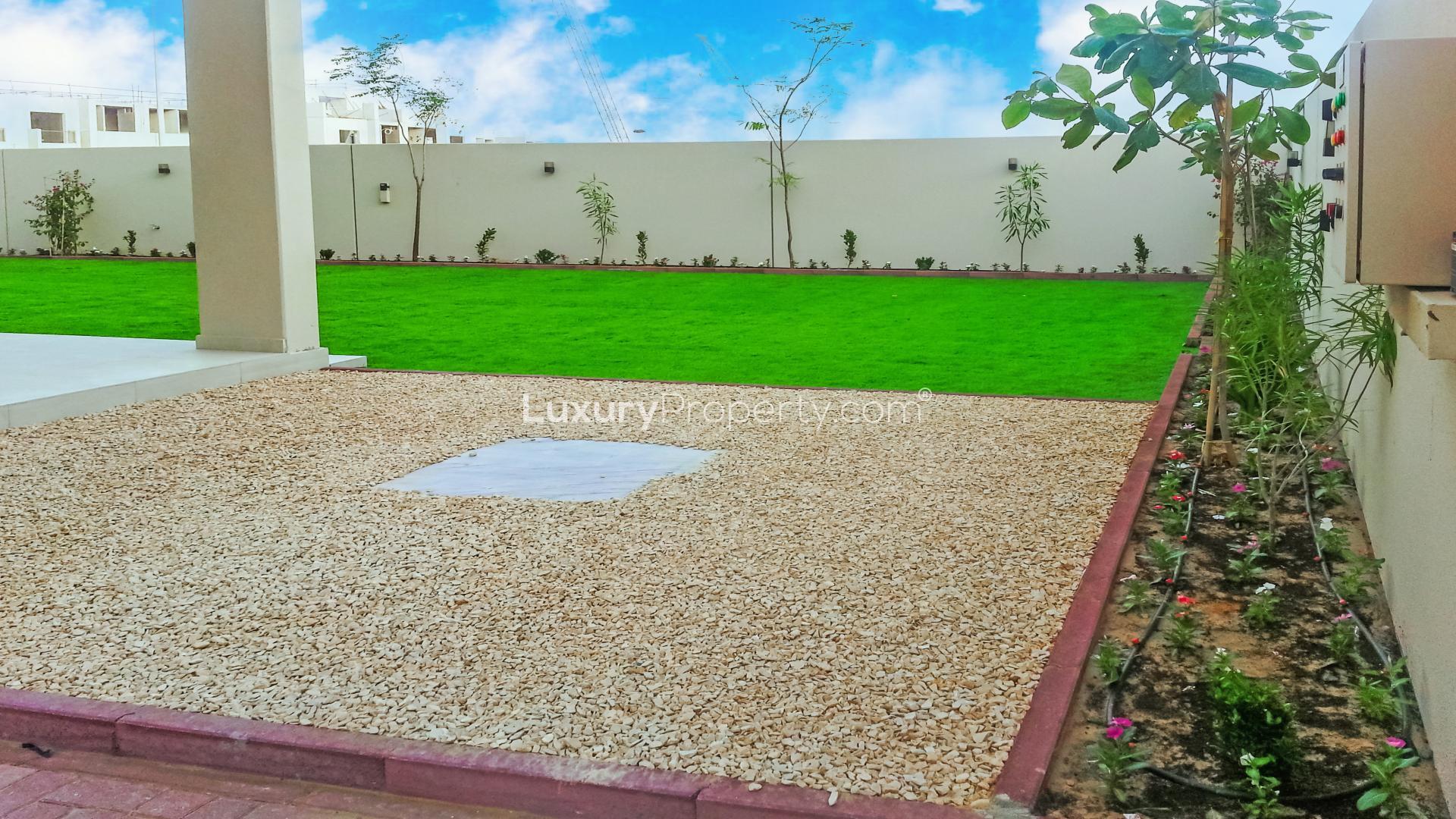 "Spacious lawn of 5-bedroom villa in Meydan Gated Community, Dubai for sale.",Luxurious Meydan villa garden with lush lawn and landscaped gravel area