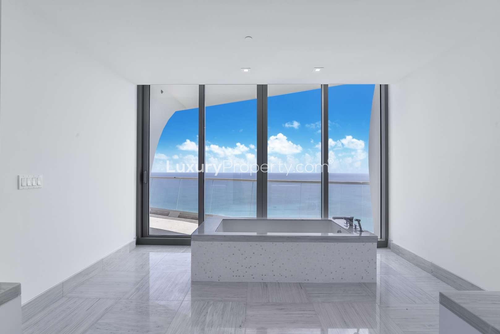 Luxurious Miami villa bathroom with ocean view, featuring modern tub and floor-to-ceiling windows