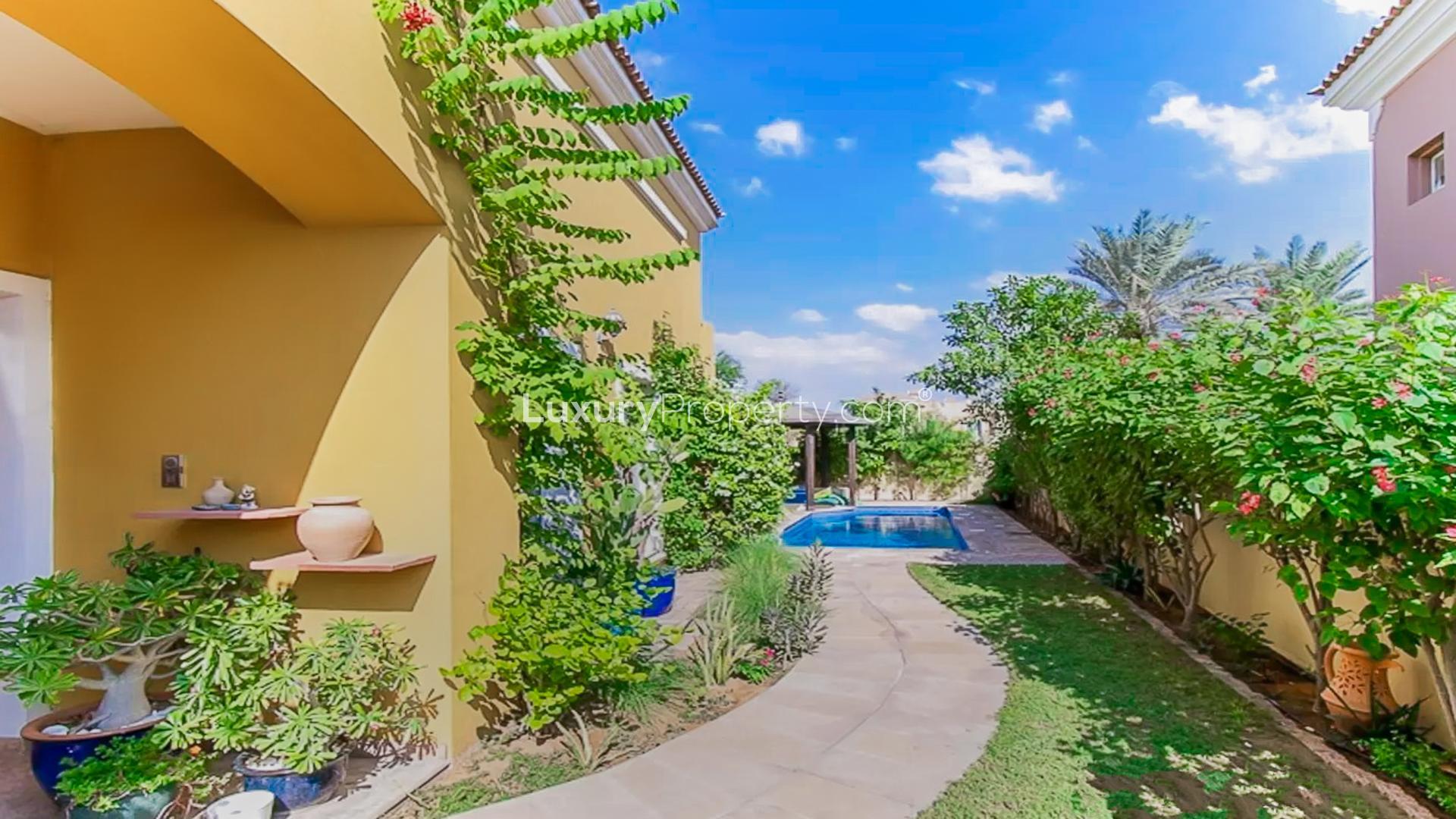 "Elegant villa exterior in Mirador, Arabian Ranches with lush palm trees and sunny facade.",Beautiful garden and pathway leading to pool in Mirador villa, Arabian Ranches