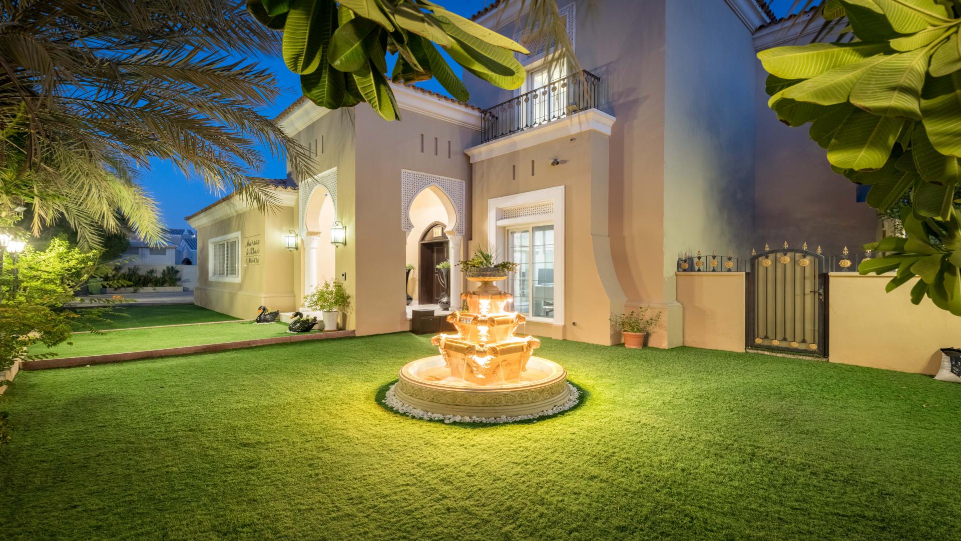 "Luxurious five-bedroom villa exterior at night in Arabian Ranches Polo Homes community.",Luxurious Polo Home villa exterior with fountain in Arabian Ranches, available for rent