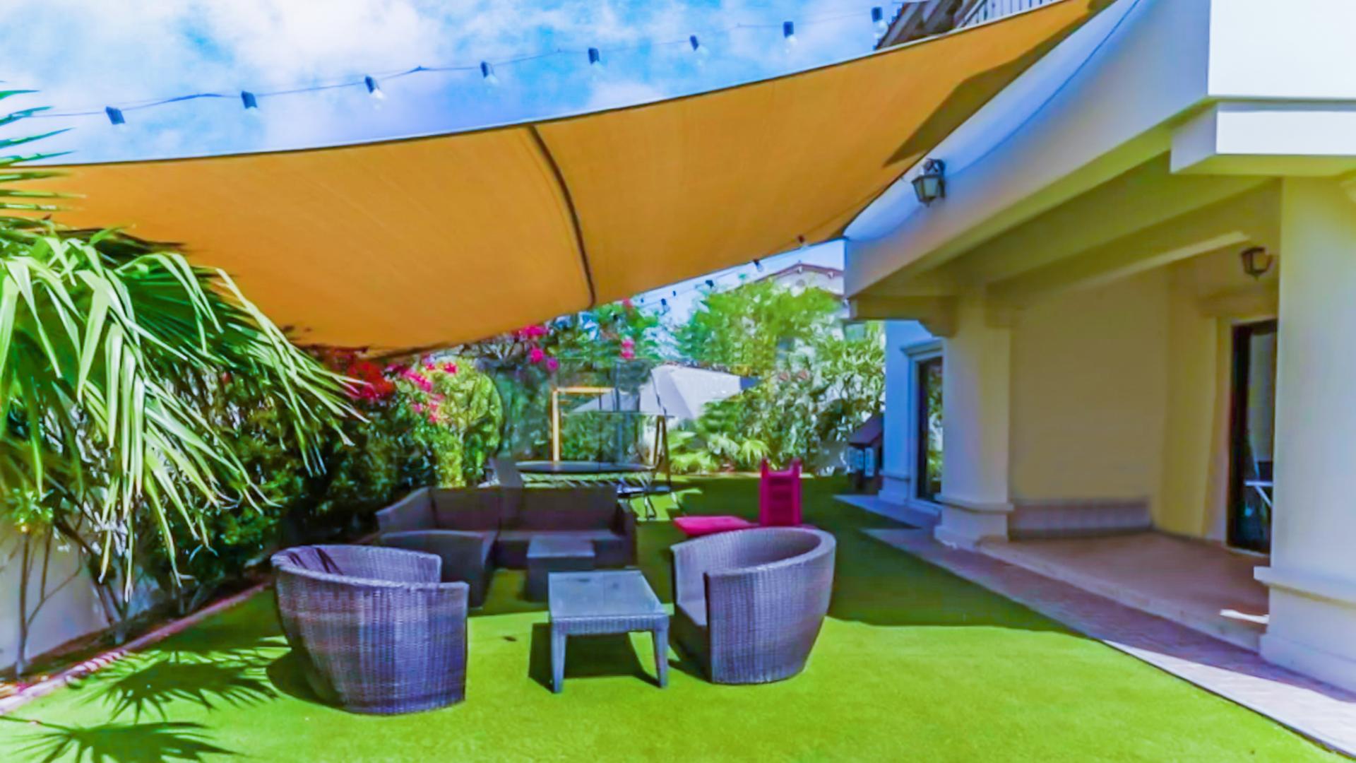 "Spacious backyard of Type 4 Rosa Villa in Arabian Ranches 2 with green lawn and swing.",Outdoor patio area of Type 4 Rosa Villa in Arabian Ranches 2, Dubai