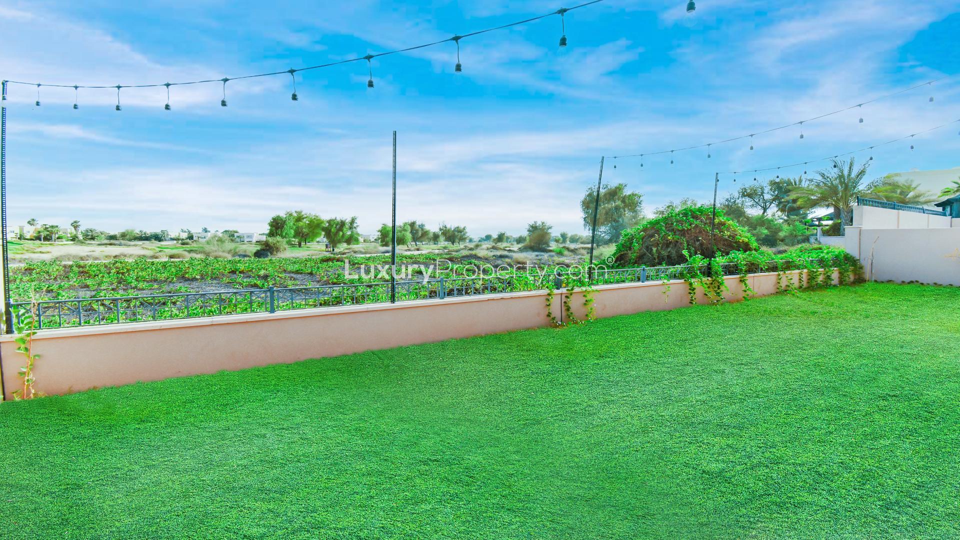 "Spacious backyard of Type 3 Villa in Arabian Ranches with golf course view.","Spacious villa garden with golf course view in Savannah, Arabian Ranches community.",Spacious living room in Type 3 villa, Arabian Ranches, Savannah, with modern stone accent wall