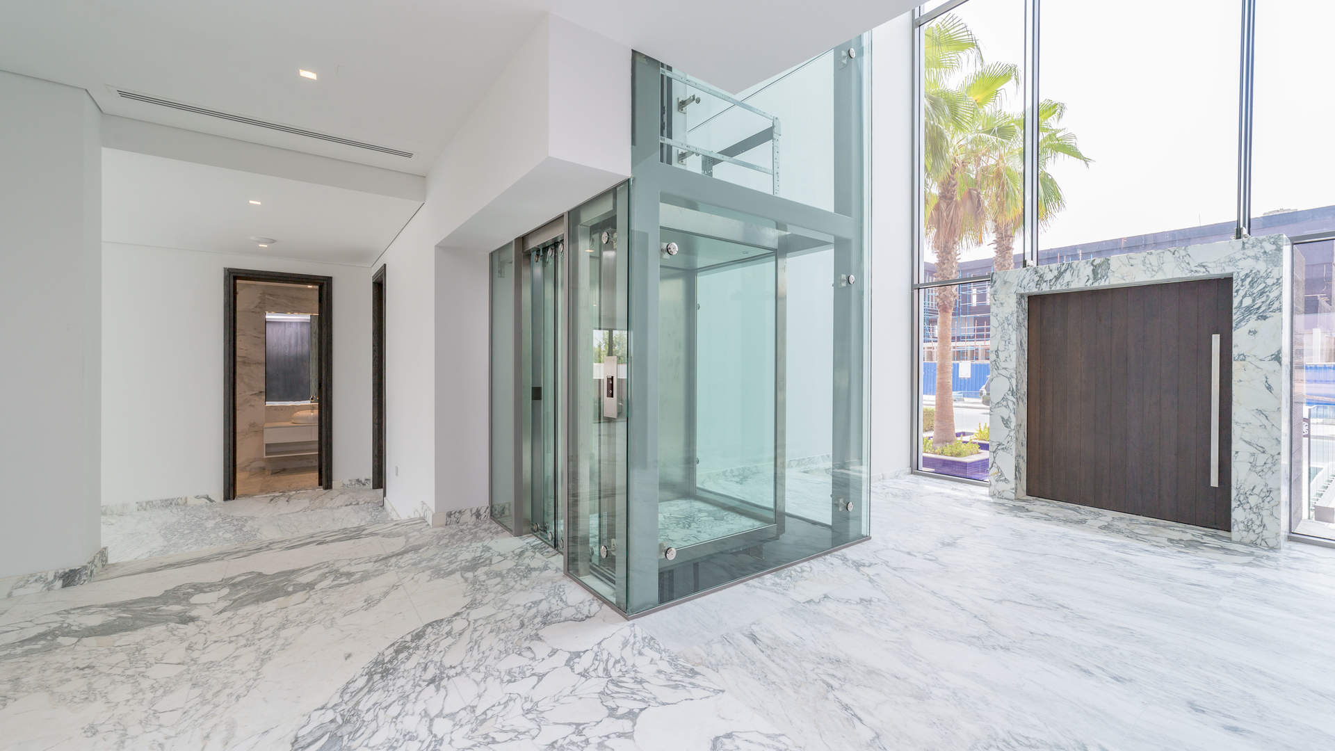 "Luxury beachfront villa pool view at Palm Jumeirah Signature Villas, Dubai, for sale.",Luxurious marble interior with modern glass elevator in Palm Jumeirah beachfront villa