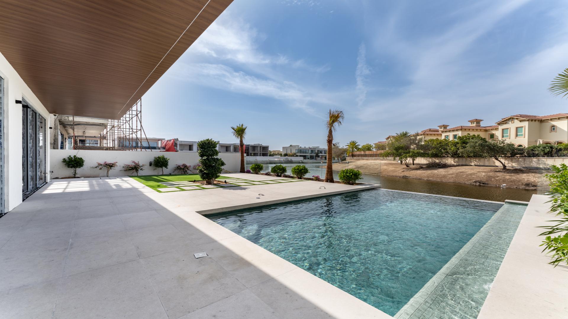 "Luxurious Jumeirah Park villa with infinity pool overlooking serene waterway, for sale.","Elegant marble staircase in Jumeirah Park 5-bedroom villa, showcasing modern luxury design.",Luxurious marble-floored living area in 5-bedroom villa, Jumeirah Park, with large glass doors