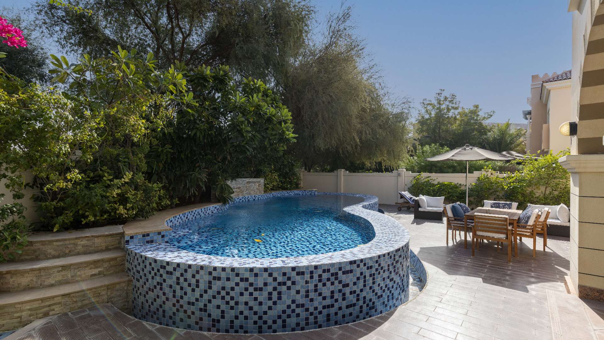 "Elegant entrance of 5-bed villa in Victory Heights, featuring stylish staircase and decor.","Luxury villa with private pool and garden in Victory Heights, Dubai Sports City.",Hallway view in luxury villa, featuring a cozy reading room with bookshelves