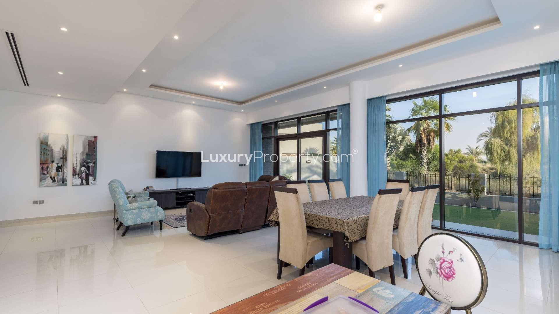 "Stunning 5-bedroom villa with golf view in Damac Hills, Whitefield community, for sale.",Luxurious living room with garden view in Damac Hills Whitefield villa, for sale