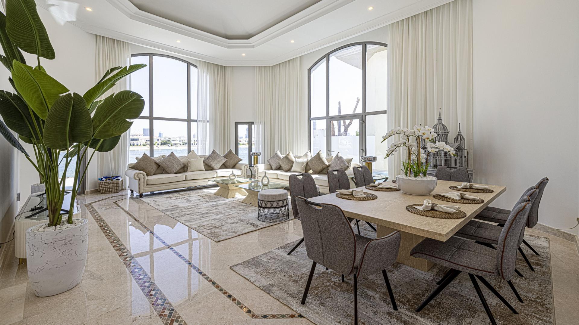 Modern furnished living and dining area in Palm Jumeirah villa, featuring large windows and decor