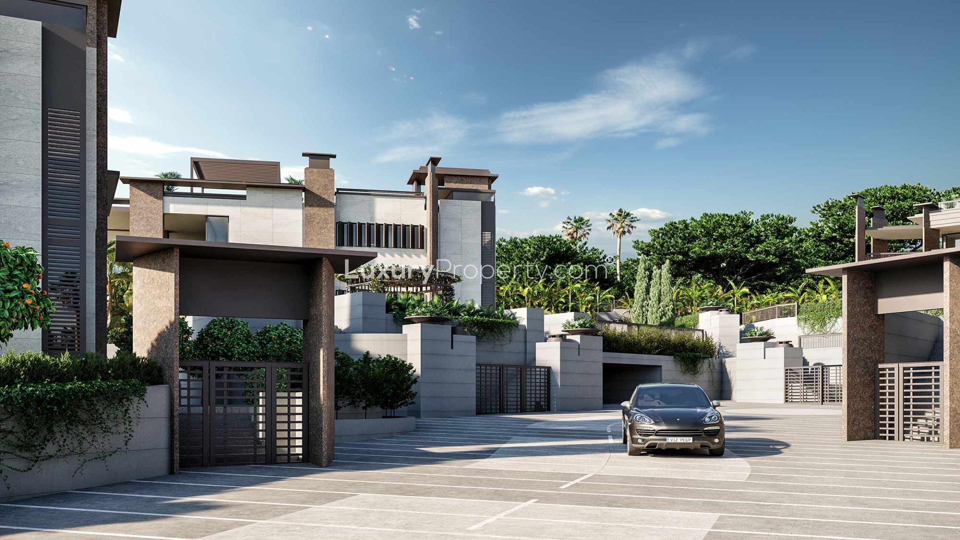 Luxury villa exterior in gated Marbella community, surrounded by palm trees and modern architecture