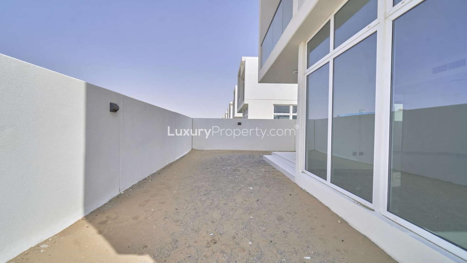 Side view of Adria Villas townhouse exterior, Damac Hills 2, showing sandy pathway