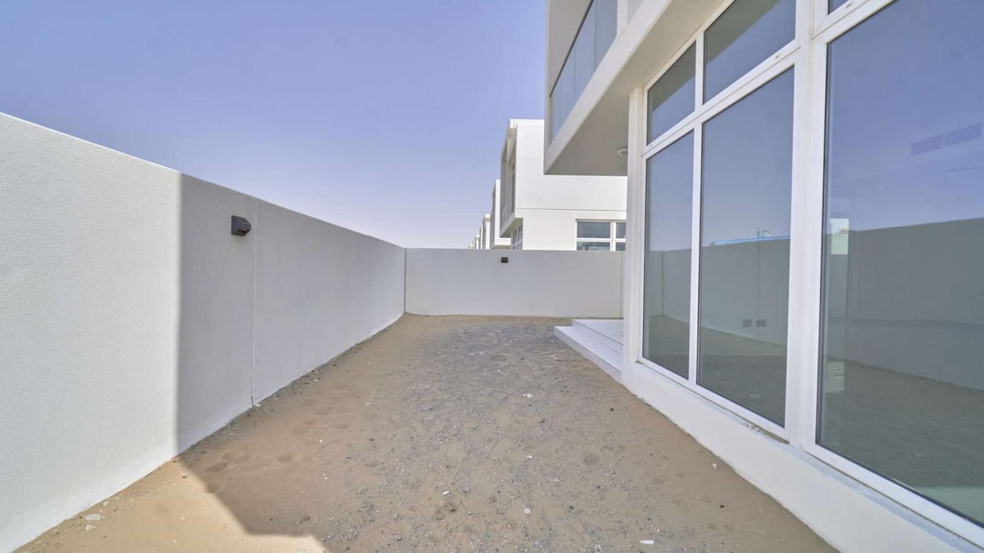 Side view of Adria Villas townhouse exterior, Damac Hills 2, showing sandy pathway