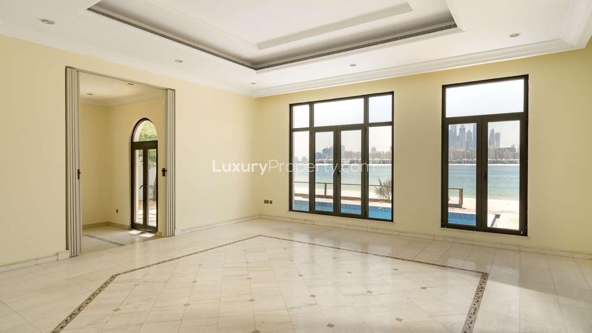 "Spacious villa interior with beachfront view, located in Palm Jumeirah's Signature Villas community.",Interior view of Palm Jumeirah villa with beachfront and city skyline through large windows