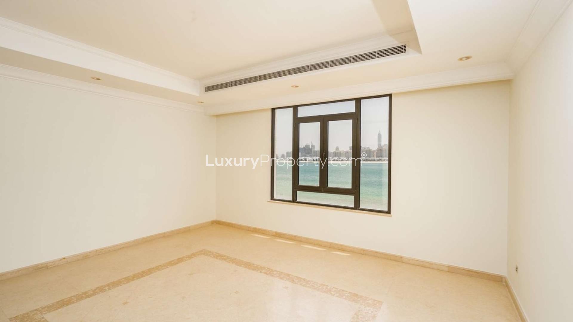 "Exquisite 6-bedroom beachfront villa exterior in Palm Jumeirah's Signature Villas community.",Empty room with large window and sea view in Palm Jumeirah villa