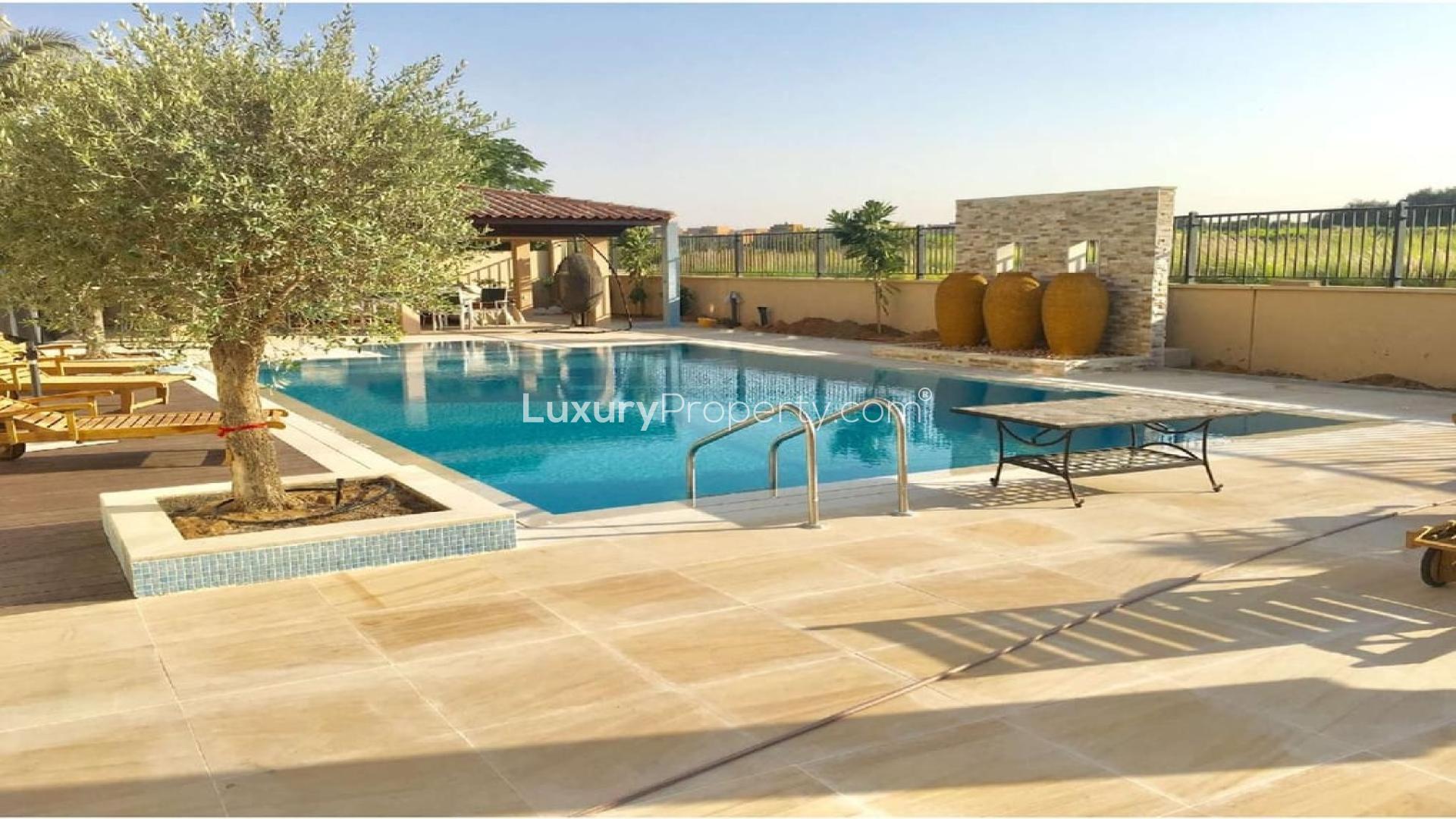 Luxurious villa poolside view in La Avenida, Arabian Ranches, with sun loungers and garden