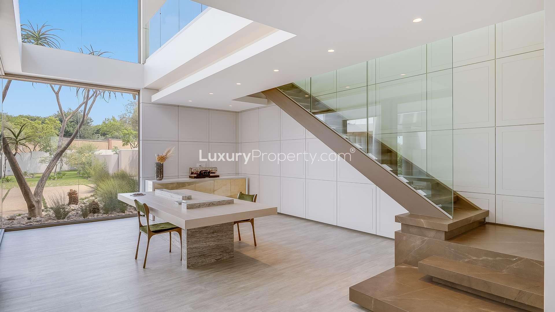 Luxury villa interior with modern dining area, large windows, and garden view in Waterfall City