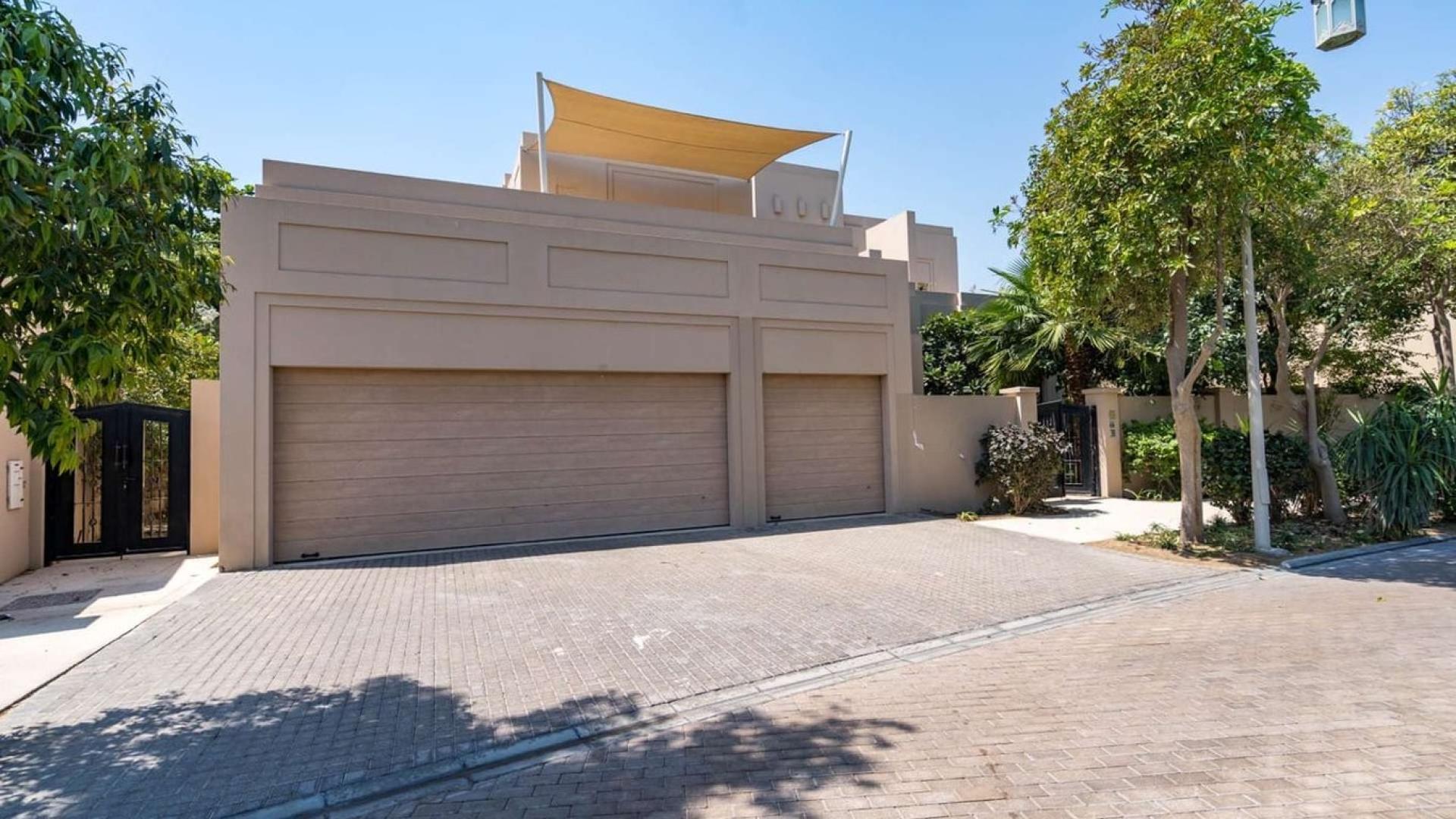 "Spacious Ajman Uptown villa exterior with garage and lush greenery, for sale.",Modern Desert Leaf Villa exterior with garage, trees, and driveway in Ajman Uptown