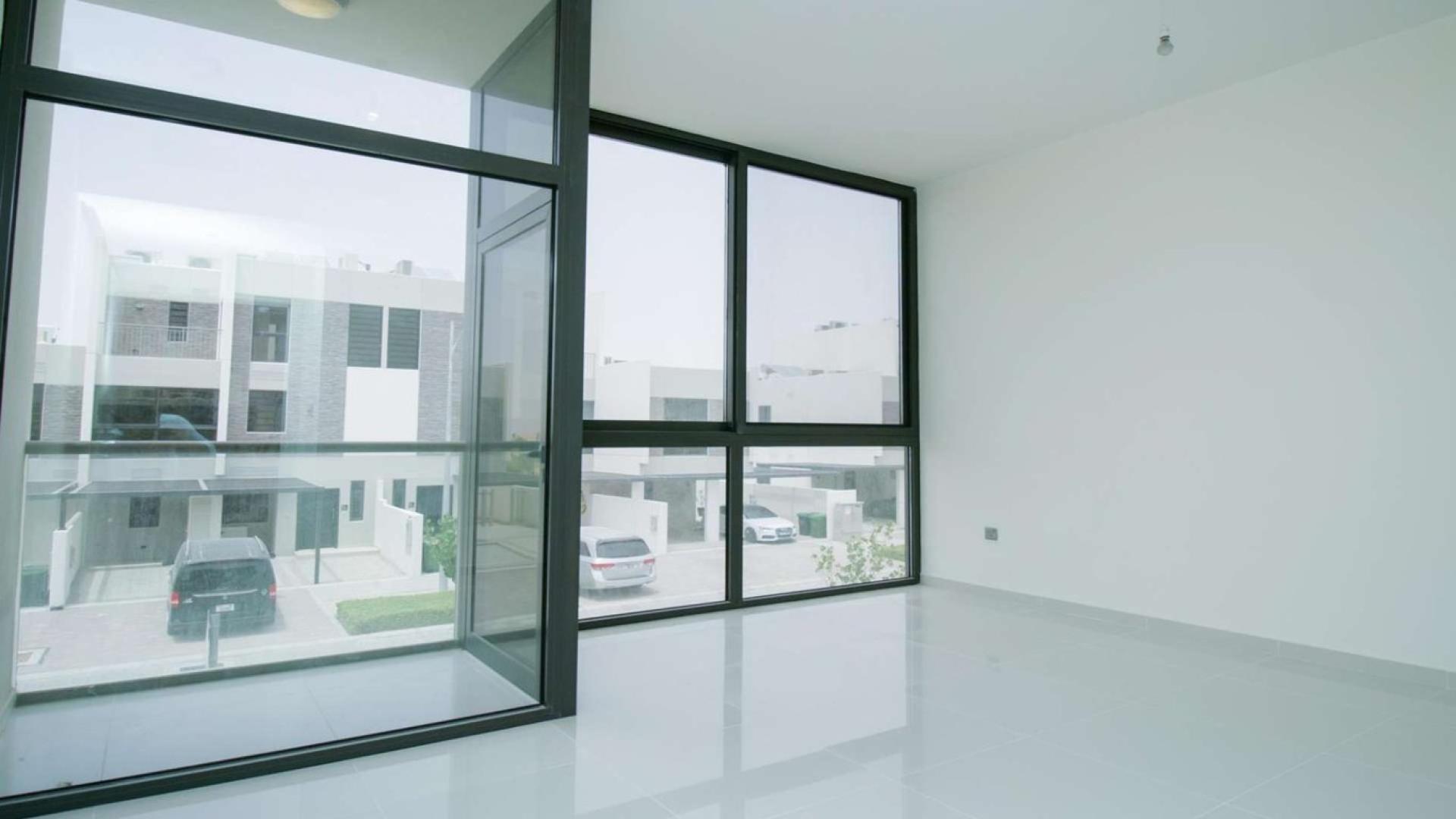 Bright, spacious bedroom in six-bedroom villa, Damac Hills 2, with built-in wardrobe and glass door