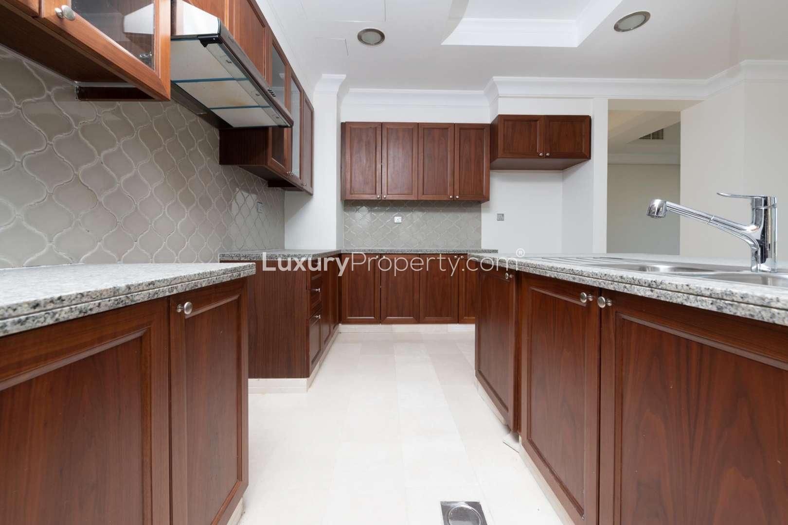 "Scenic view from six-bedroom villa in Aseel, Arabian Ranches, showcasing green landscape.",Luxurious kitchen with wooden cabinets in six-bedroom Aseel villa, Arabian Ranches for rent