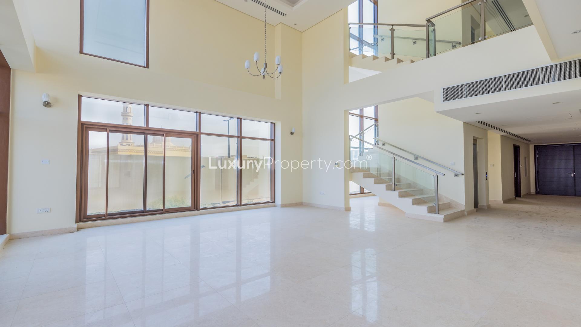 "Modern six-bedroom villa exterior in Meydan Gated Community, available for rent in Dubai.",Spacious living area in six-bedroom villa, Grand Views, Meydan, with modern staircase and windows
