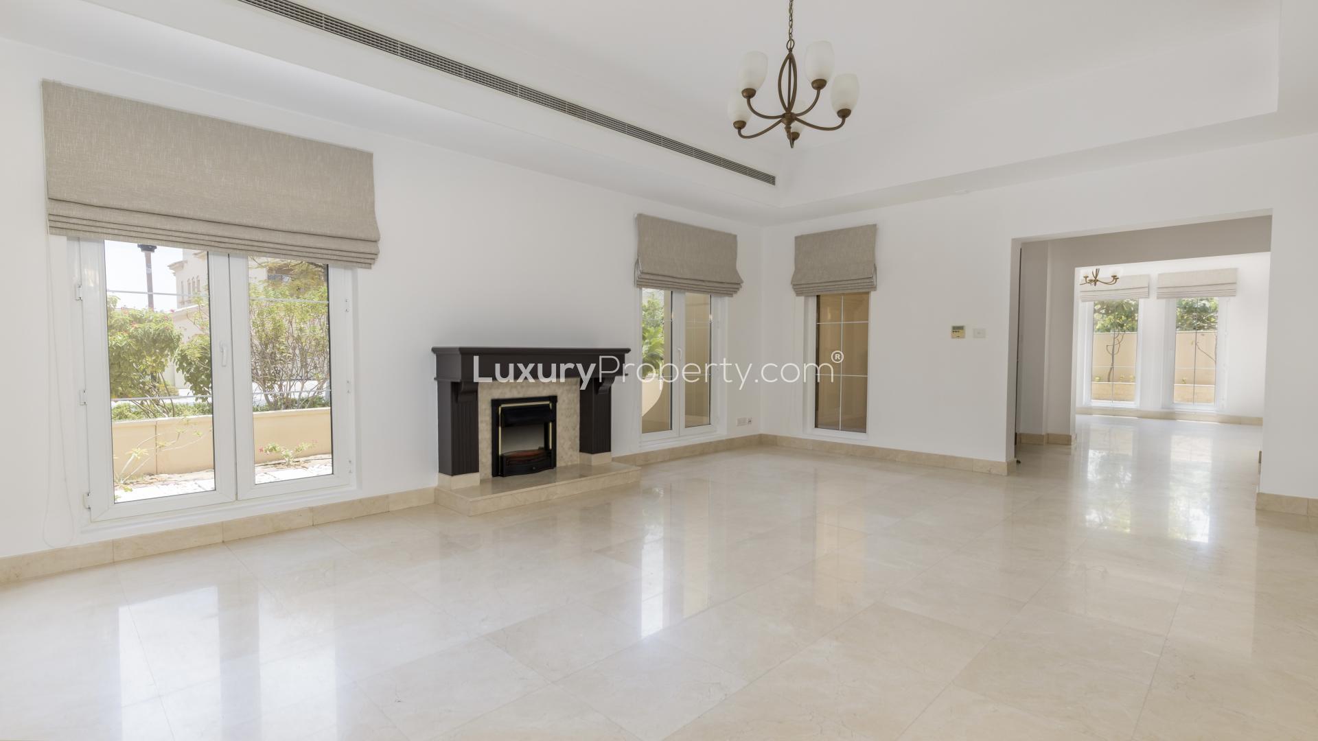 Elegant living room in 6-bedroom Mirador villa, Arabian Ranches, featuring fireplace and large windows