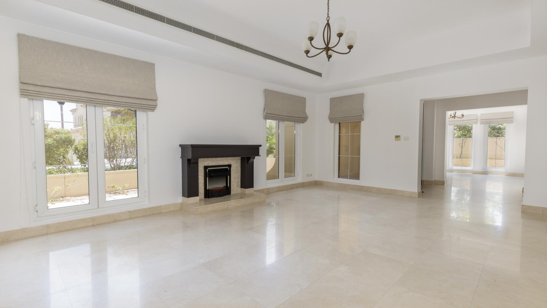 Elegant living room in 6-bedroom Mirador villa, Arabian Ranches, featuring fireplace and large windows