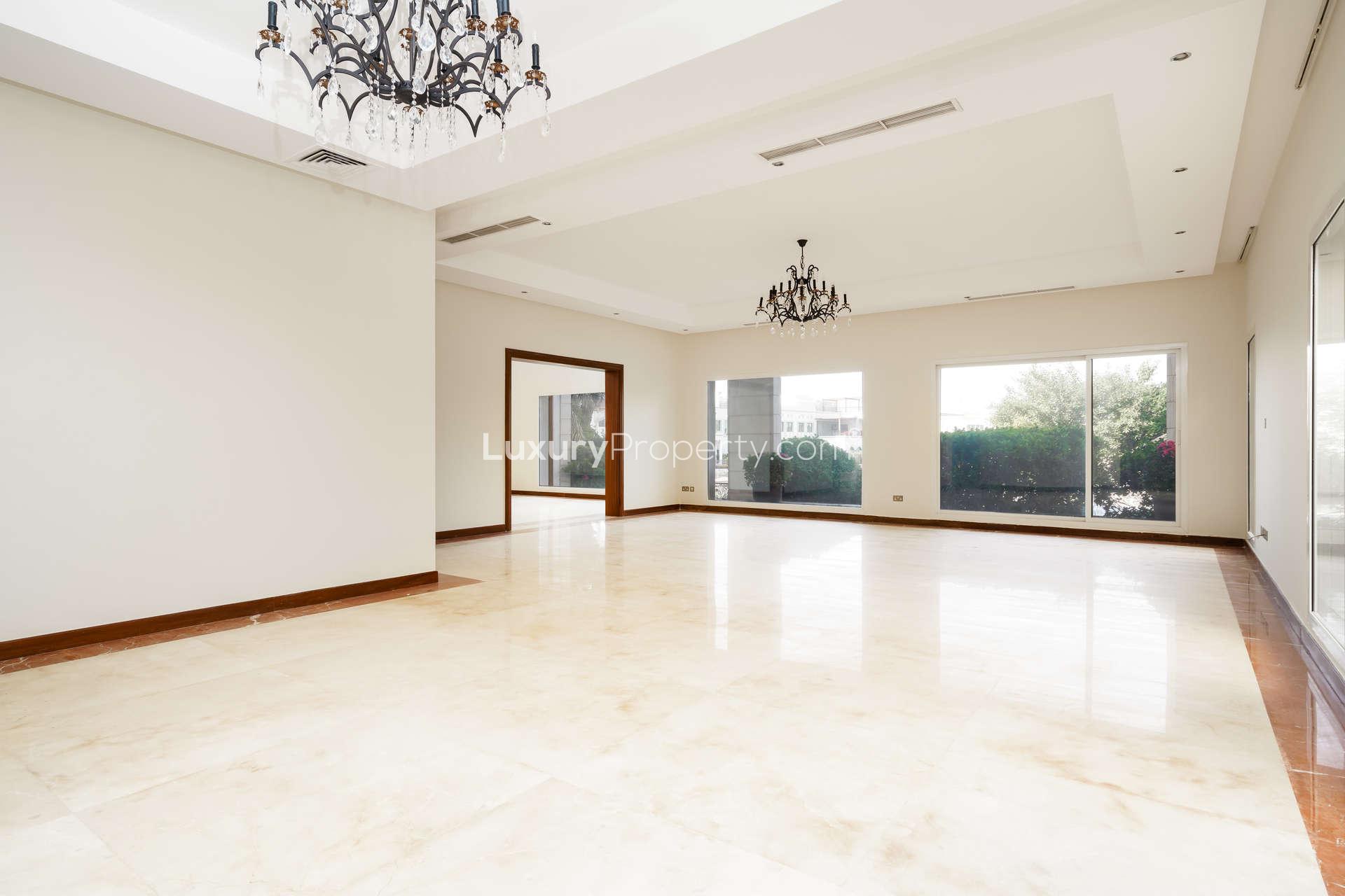 Spacious living room with chandeliers in Emirates Hills villa, marble flooring, large windows