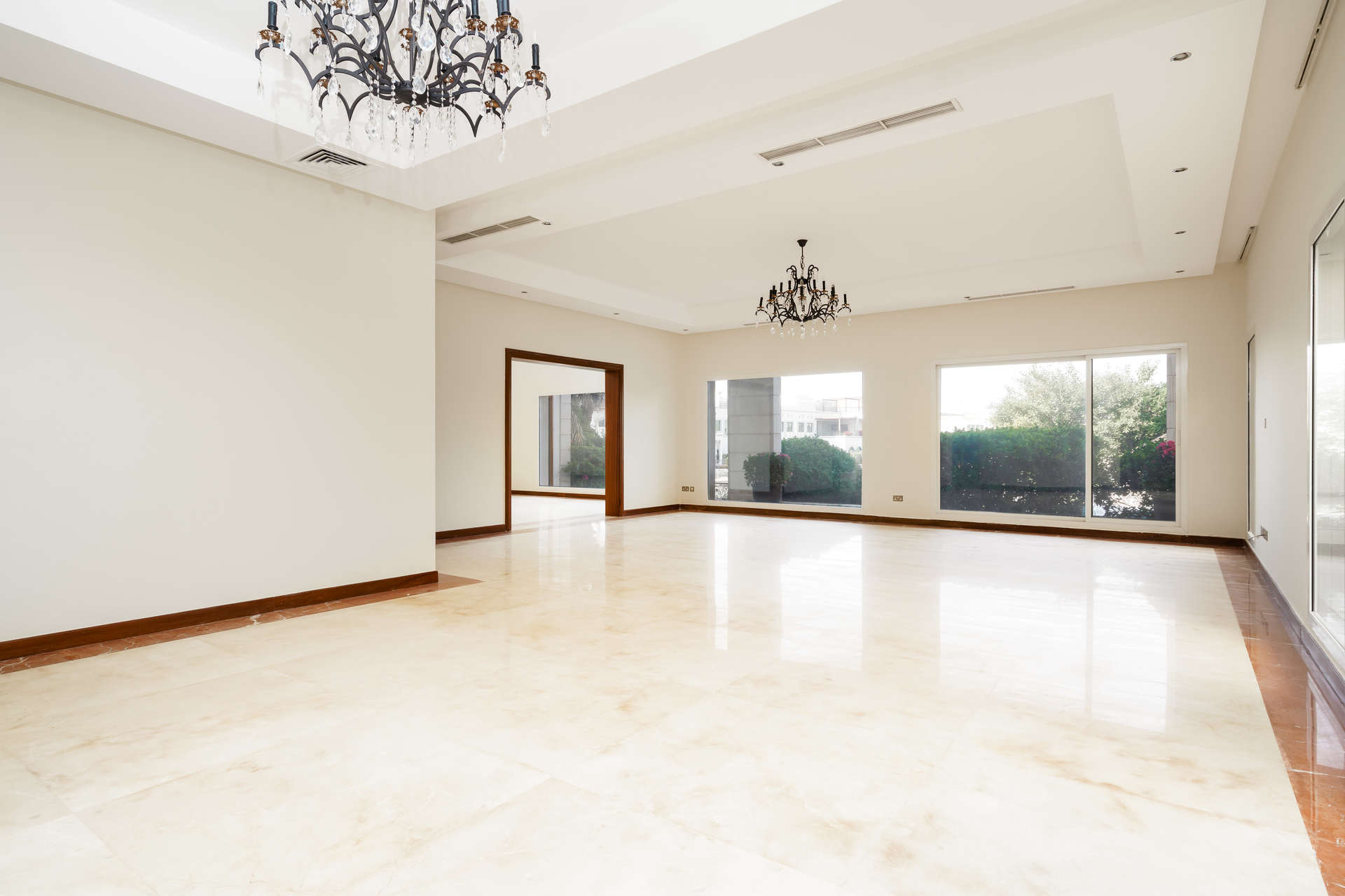 Spacious living room with chandeliers in Emirates Hills villa, marble flooring, large windows