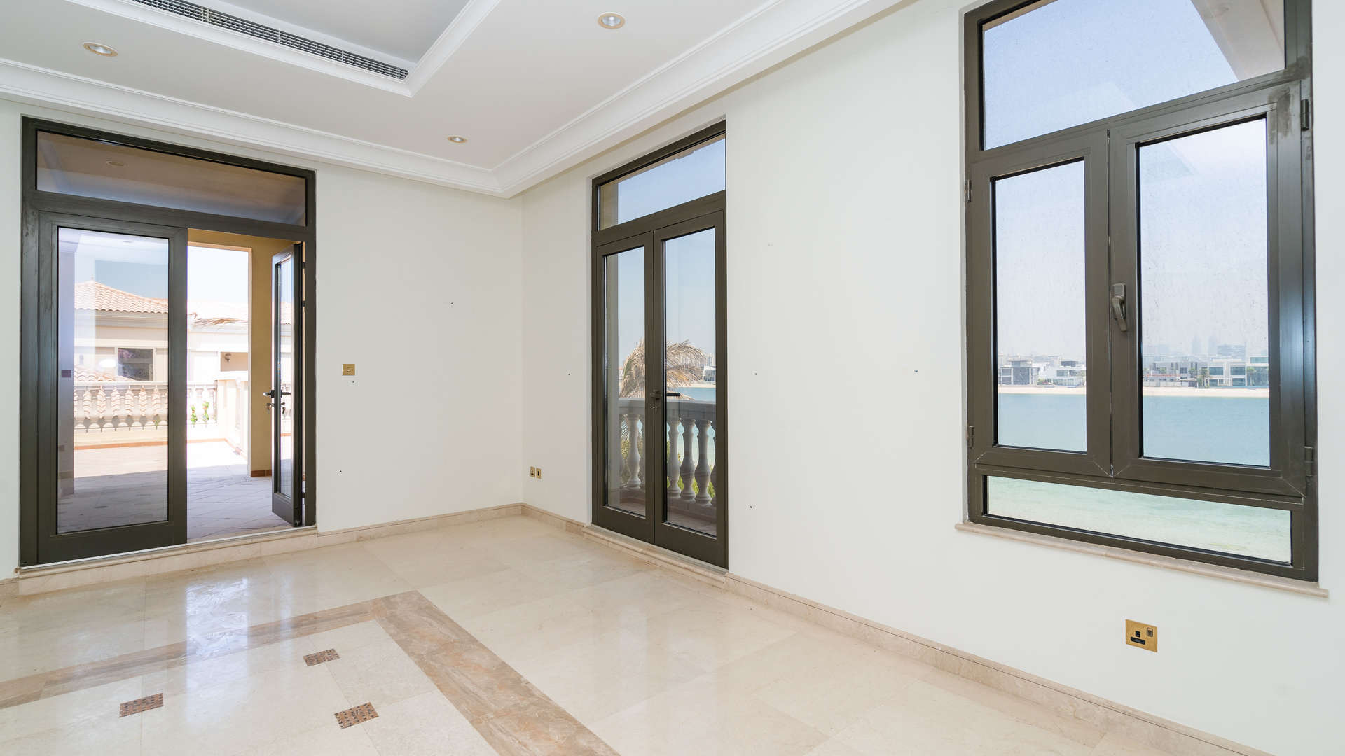 Empty room with marble floors in Palm Jumeirah villa, featuring large windows and balcony view