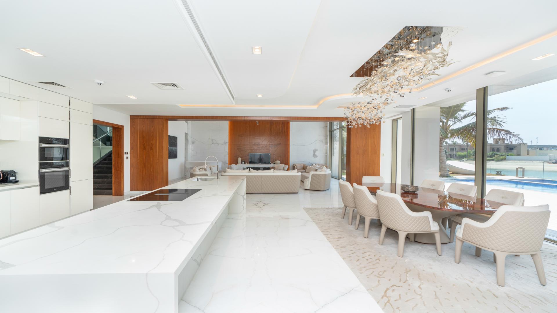 Luxurious open-plan kitchen and dining area in Palm Jumeirah villa, overlooking private pool