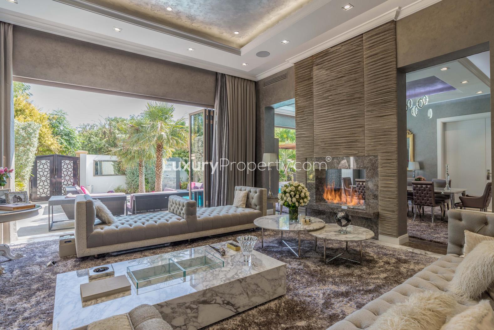 Luxurious living room in Bromellia Villa, Al Barari, with modern fireplace and garden view
