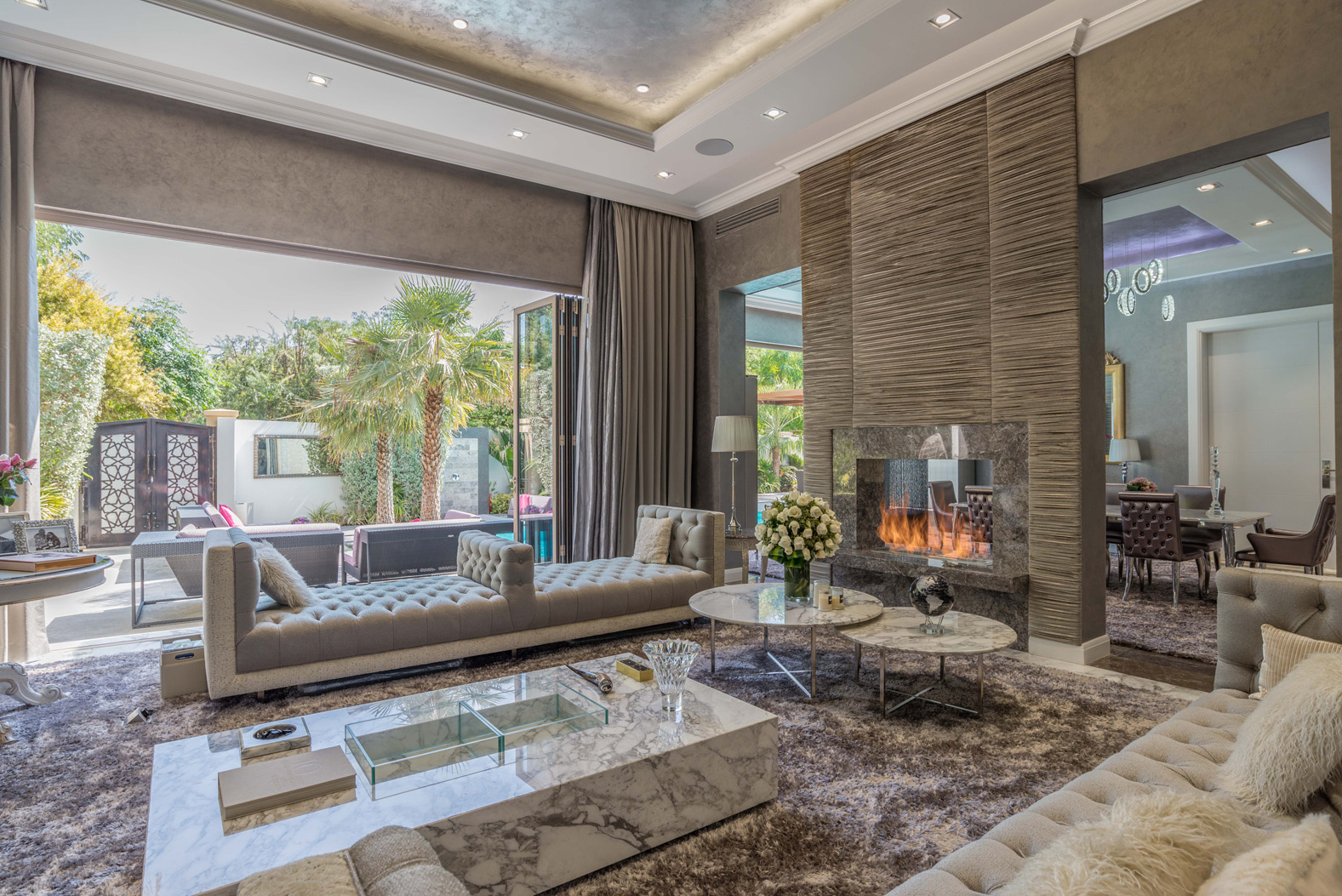 Luxurious living room in Bromellia Villa, Al Barari, with modern fireplace and garden view