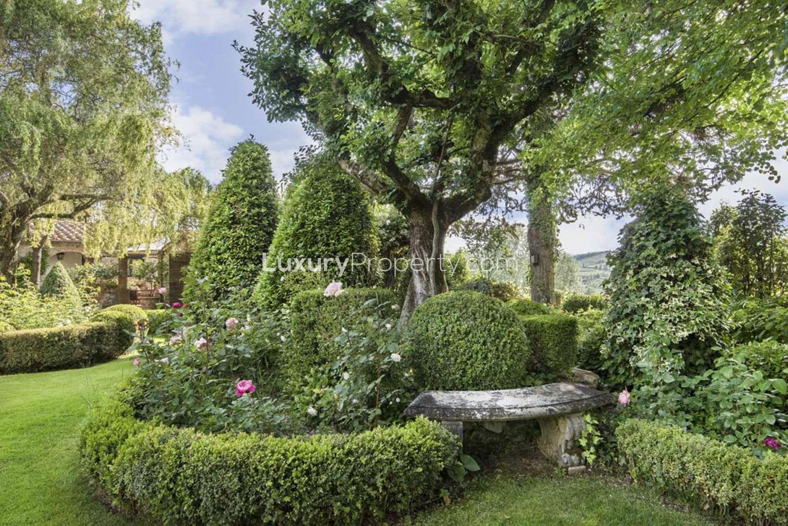 Elegant stone villa with pool in Chianti, surrounded by lush greenery and vineyards