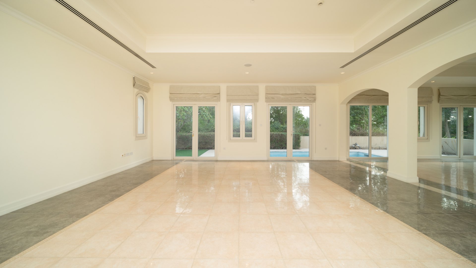 Spacious villa living room with large windows and pool view in Jumeirah Golf Estates