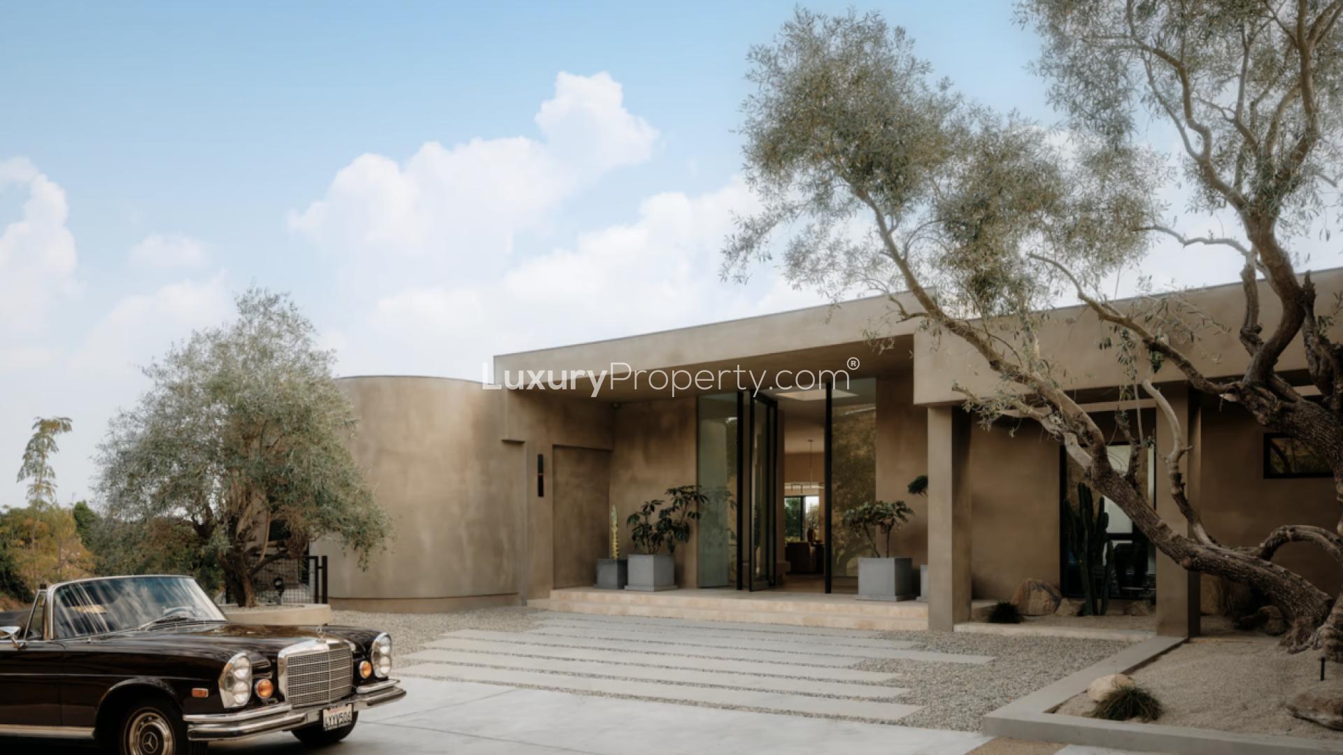 Organic modern villa exterior with pool, panoramic views in Beverly Hills, California at dusk