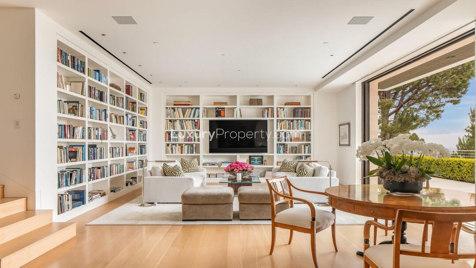 Luxurious living room in spacious Beverly Hills villa with built-in bookshelves and garden view