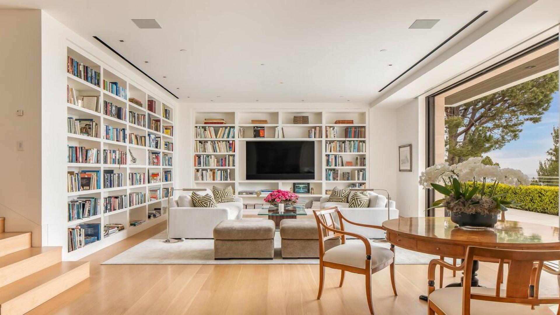 Luxurious living room in spacious Beverly Hills villa with built-in bookshelves and garden view