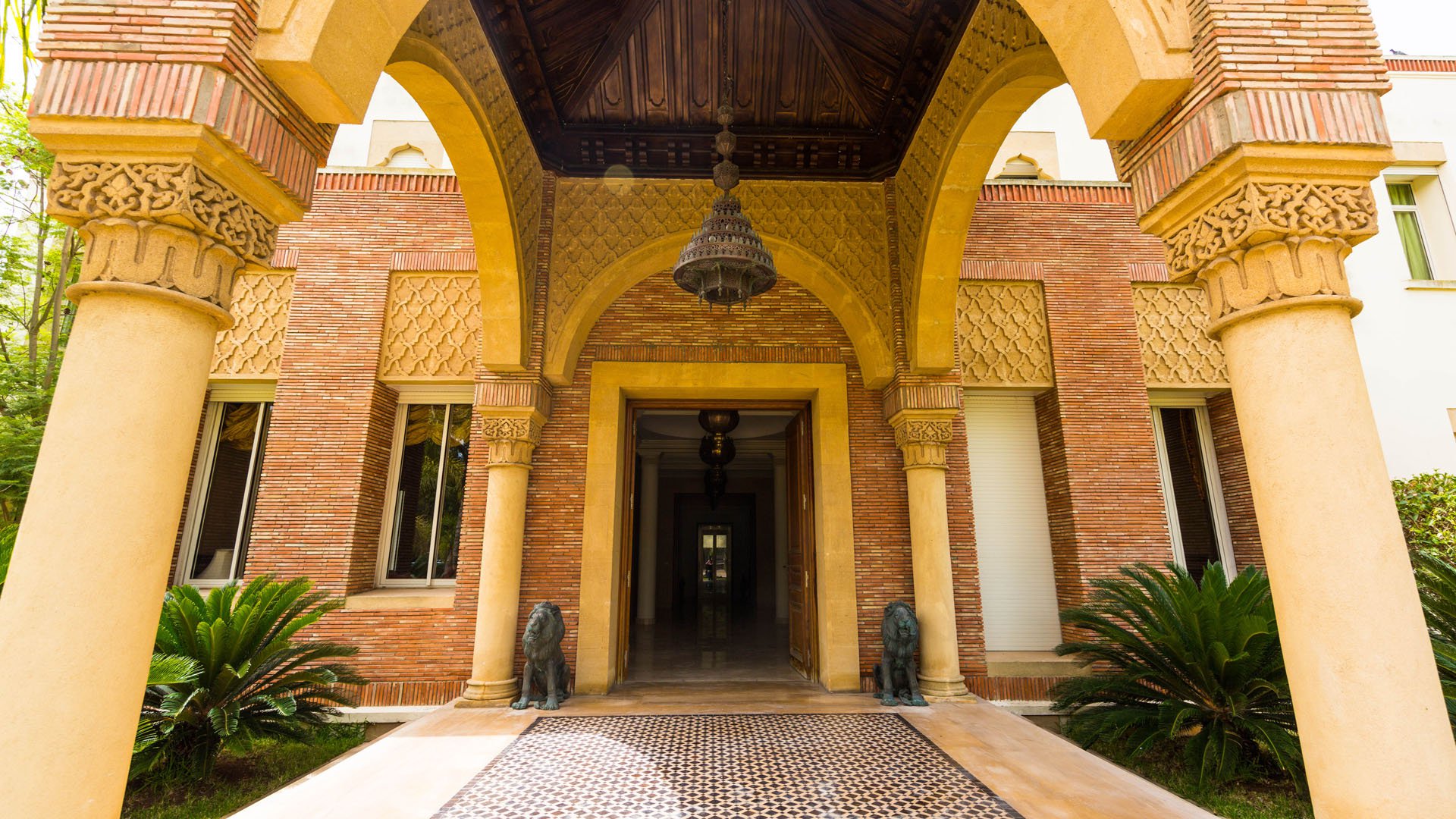 Elegant entrance of Villa Raga, Casablanca with lush gardens and intricate archway design